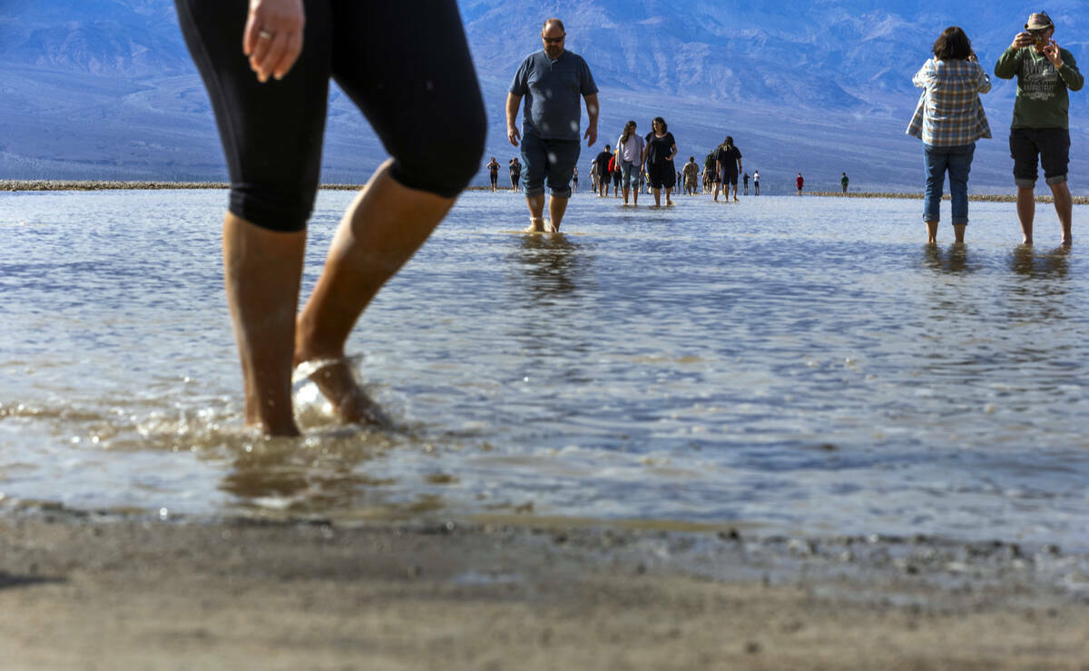 Personas entran y salen del agua en el lago temporal Manly en Badwater Basin, en el Death Valle ...