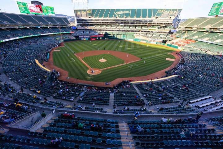 Los fans ven un partido de béisbol entre los A's y los Cincinnati Reds en el Oakland Coliseum, ...