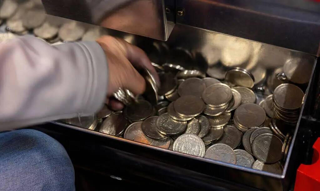 Un jugador toma monedas de un dólar de la bandeja de su máquina en Slots A Fun, la renovada z ...