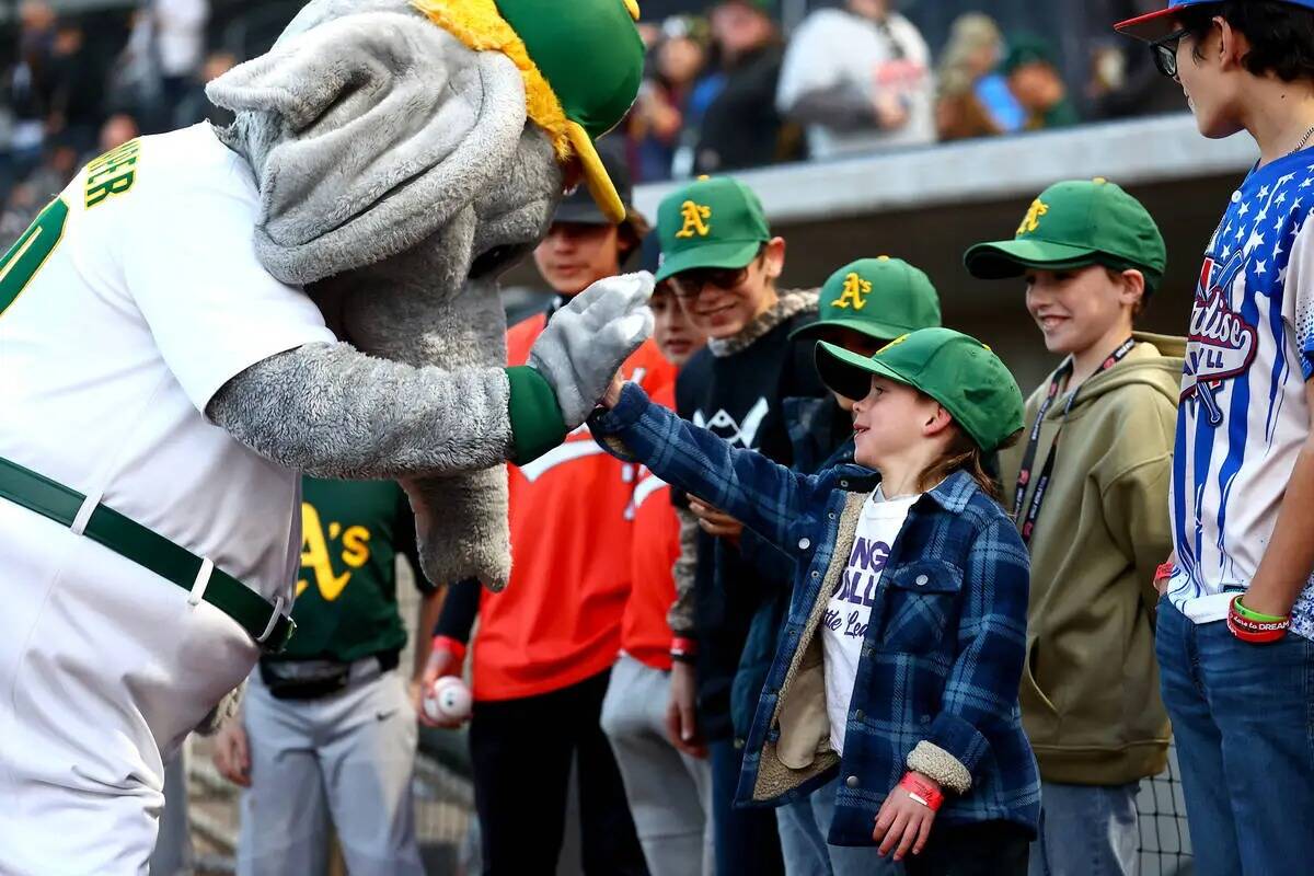 Un joven fan de los Oakland Athletics da la mano a la mascota Stomper durante un partido de exh ...
