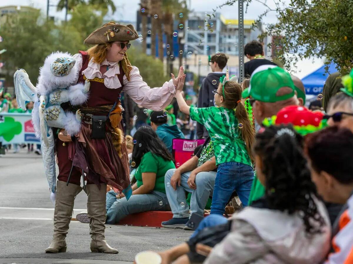 Una pirata y su dragón saludan a un joven asistente a lo largo de la ruta del desfile por Wate ...