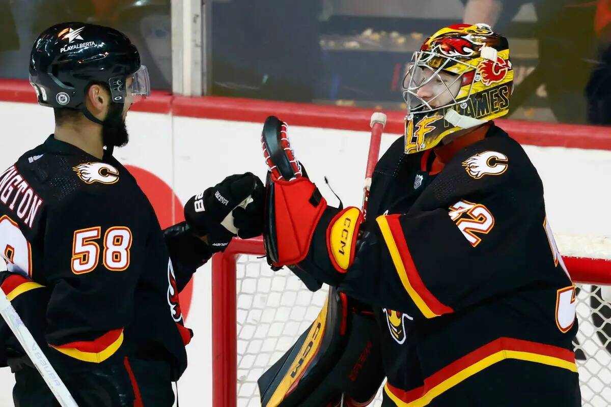 El portero de los Calgary Flames Dustin Wolf celebra con Oliver Kylington después de la victor ...