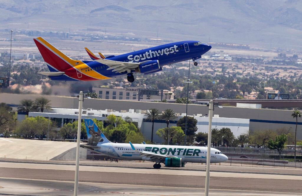 Un avión de Southwest Airlines despega mientras un avión de Frontier Airlines rueda por la pi ...