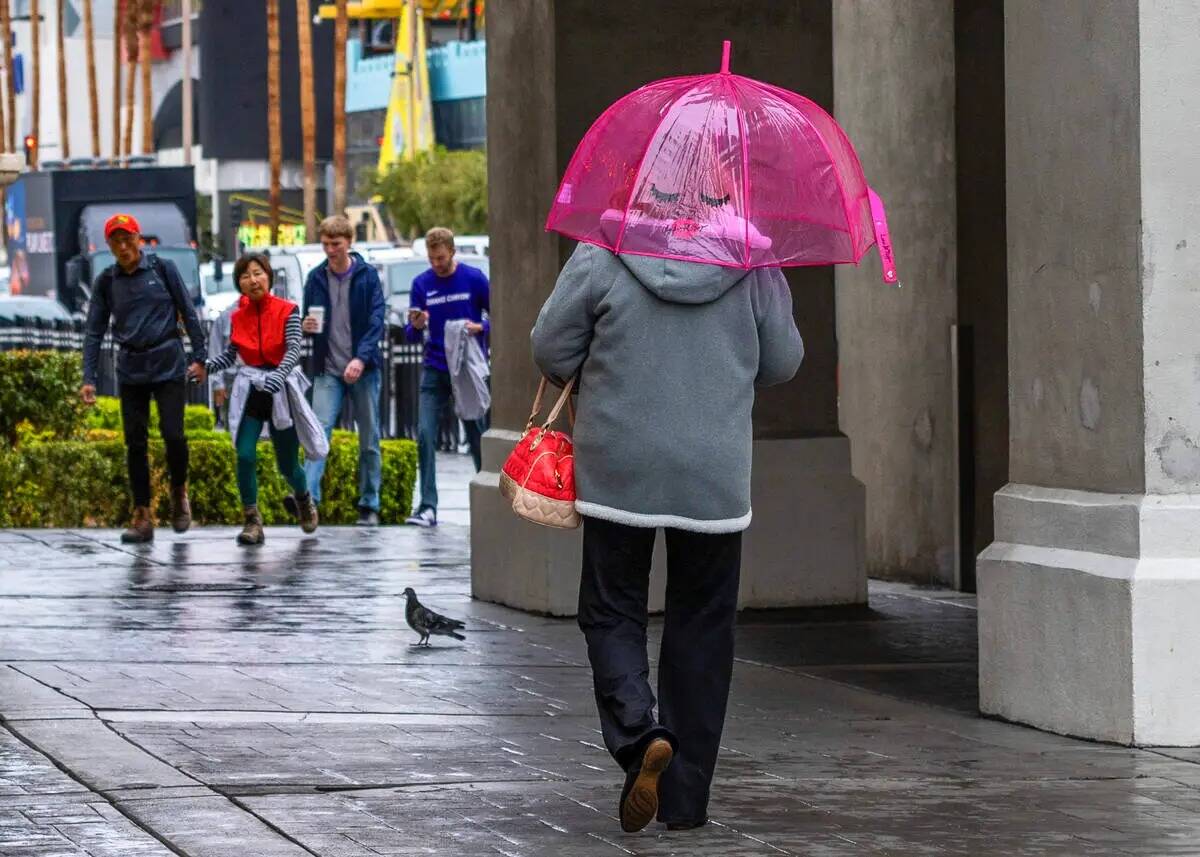 Una mujer camina con un divertido paraguas por el Strip cerca del Caesars Palace durante un dí ...