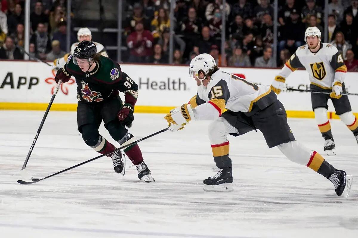 Arizona Coyotes centro Logan Cooley (92) acorrala el puck en frente de Vegas Golden Knights def ...