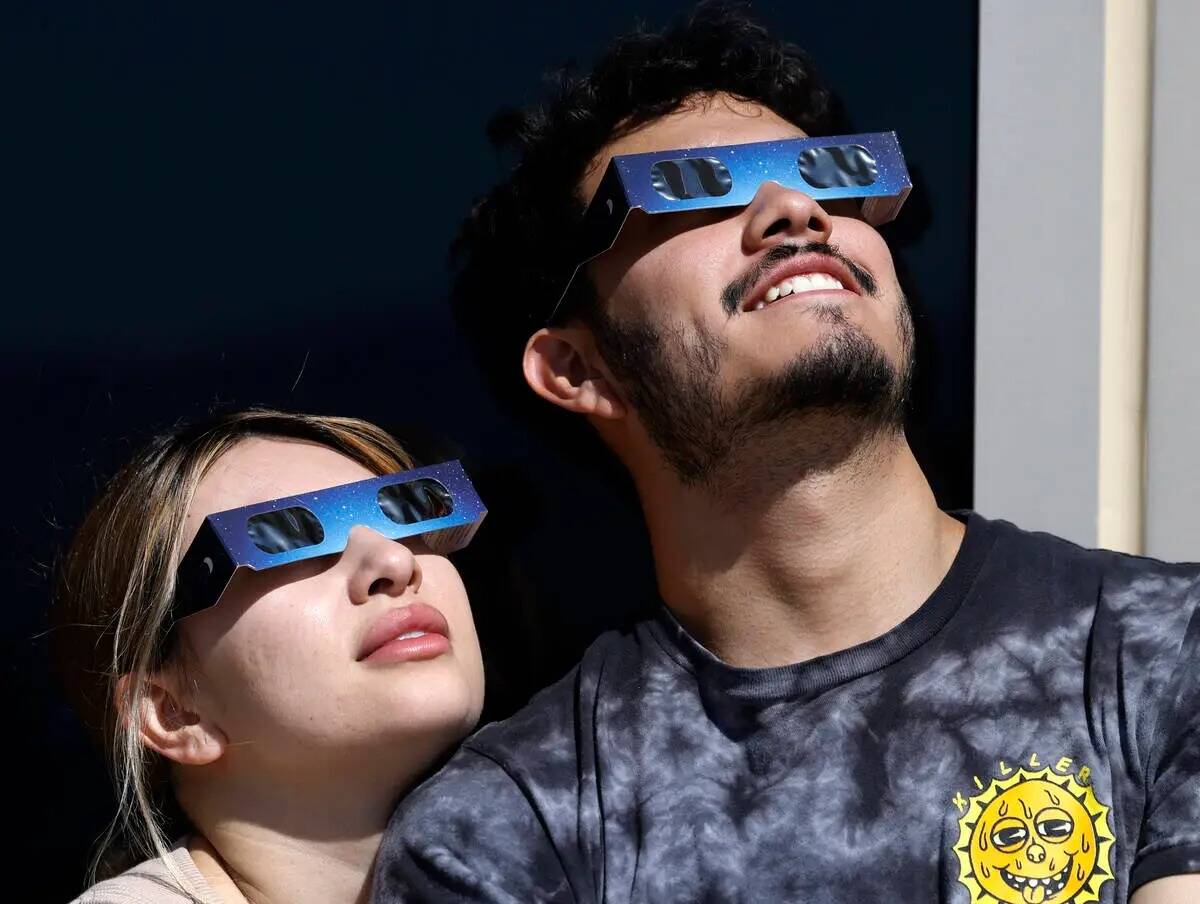 Chris Tejeda y su novia, Valentina Cernas, observan un eclipse parcial de sol en la plataforma ...