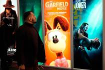Un asistente pasa junto a anuncios de próximas películas, como "The Garfield Movie" y "Joker: ...