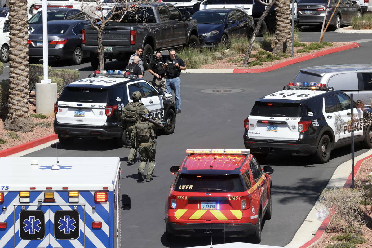 Policías de Las Vegas con un ariete y una palanca corren hacia el edificio del City National B ...