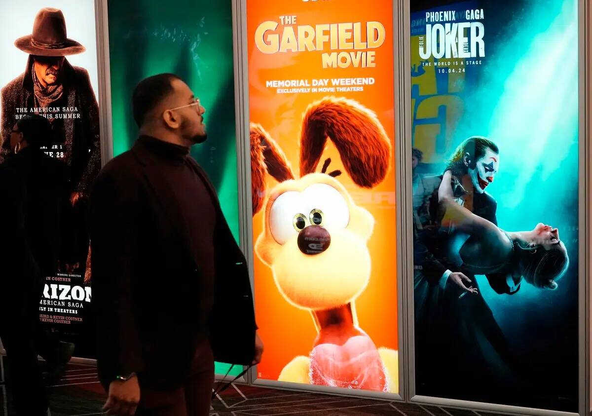 Un asistente pasa junto a anuncios de próximas películas, como "The Garfield Movie" y "Joker: ...