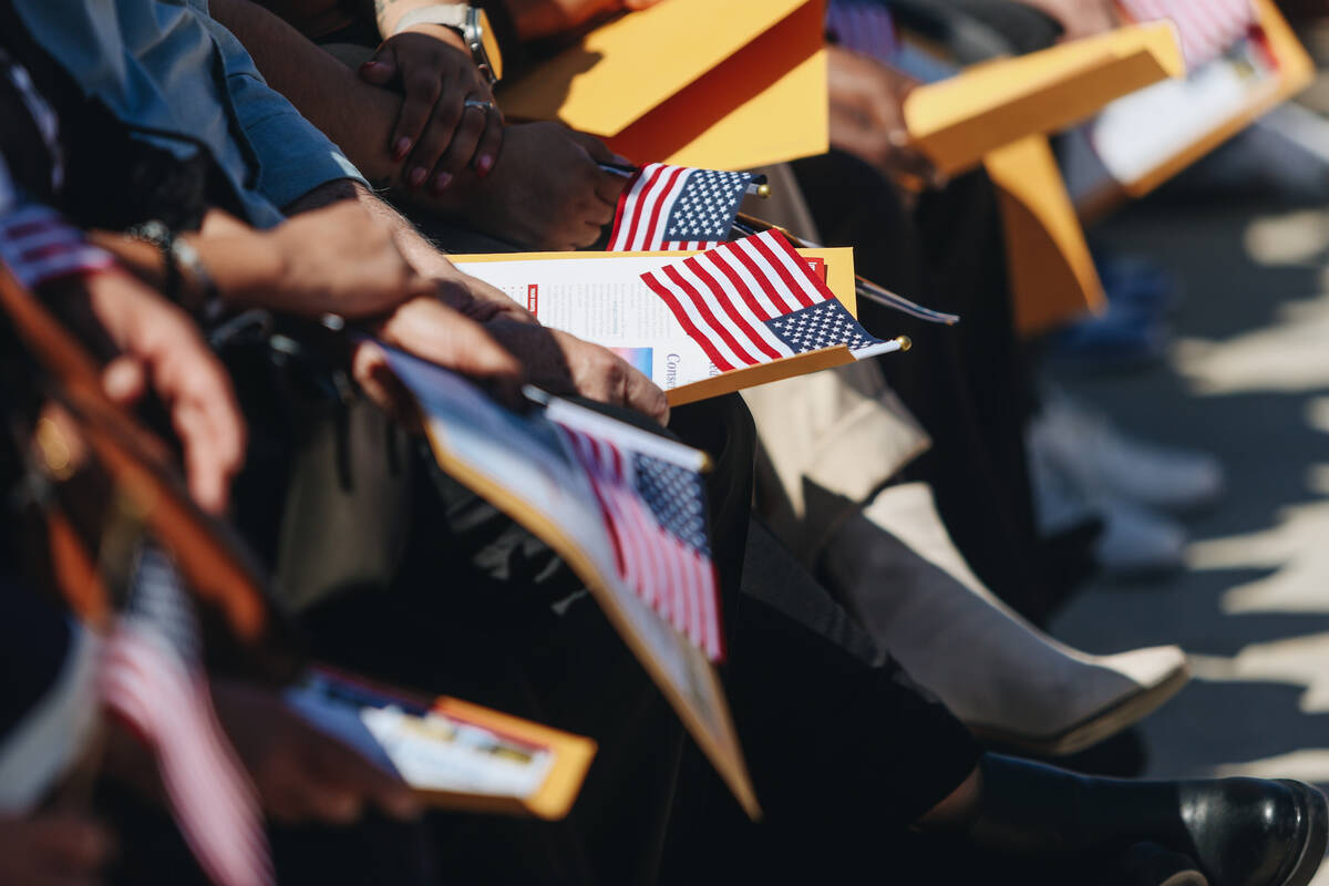 Un candidato a ciudadano estadounidense sostiene una bandera en su regazo durante un evento de ...