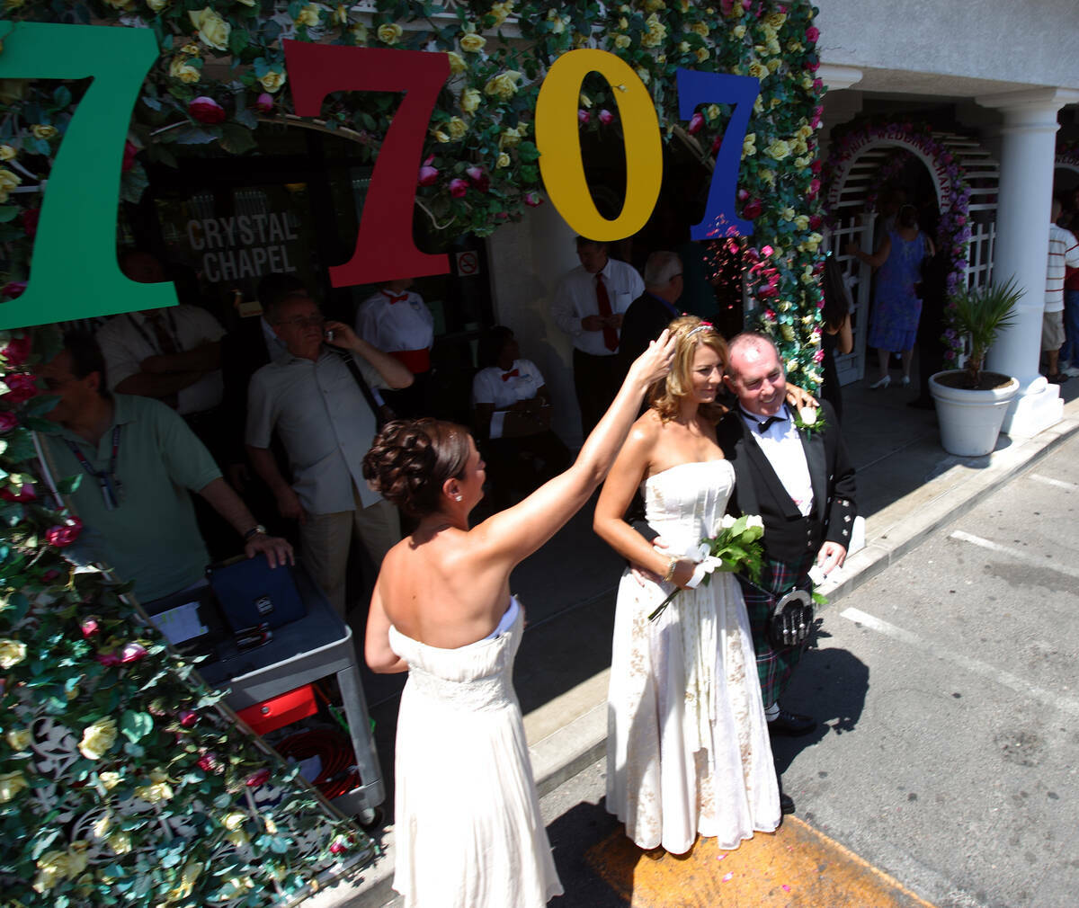 La dama de honor Anne Davie, a la izquierda, lanza pétalos de flores a los recién casados Suz ...