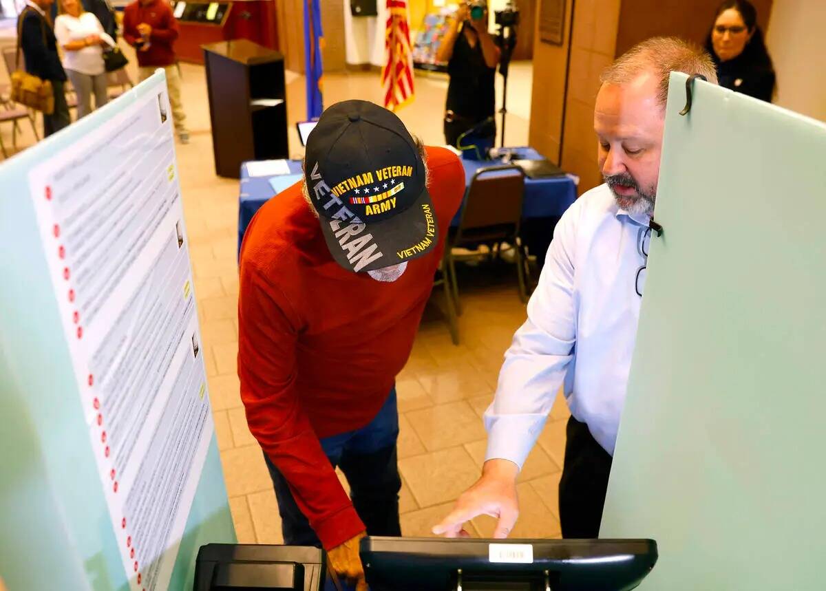 Dan Kulin, a la derecha, gerente de Administración Electoral, demuestra cómo emitir un voto a ...