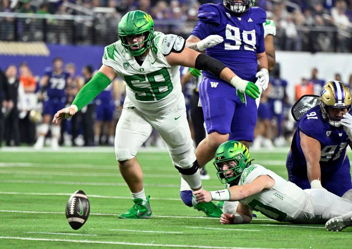 El quarterback Bo Nix (10) y el ala ofensiva Jackson Powers-Johnson (58) de Oregon van a cubrir ...