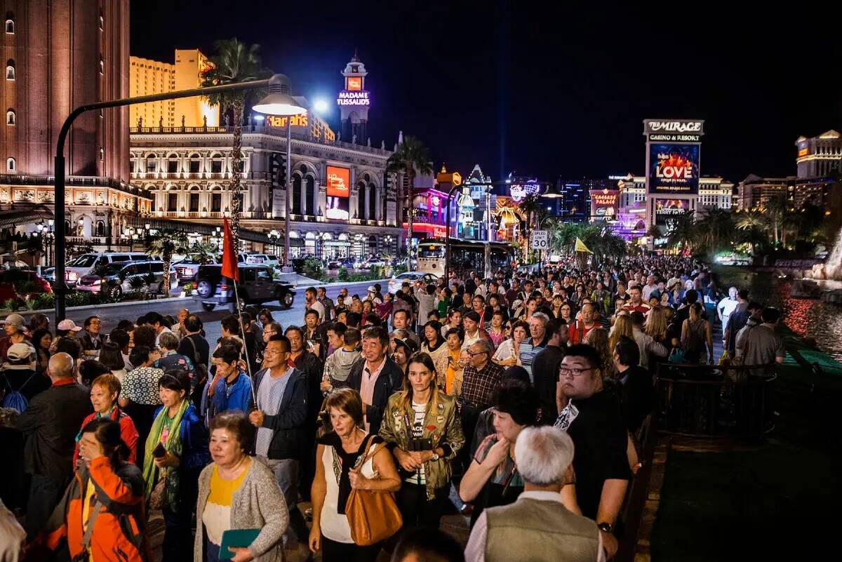 Una gran multitud deambula por el Strip de Las Vegas mientras algunos se reúnen para ver el vo ...