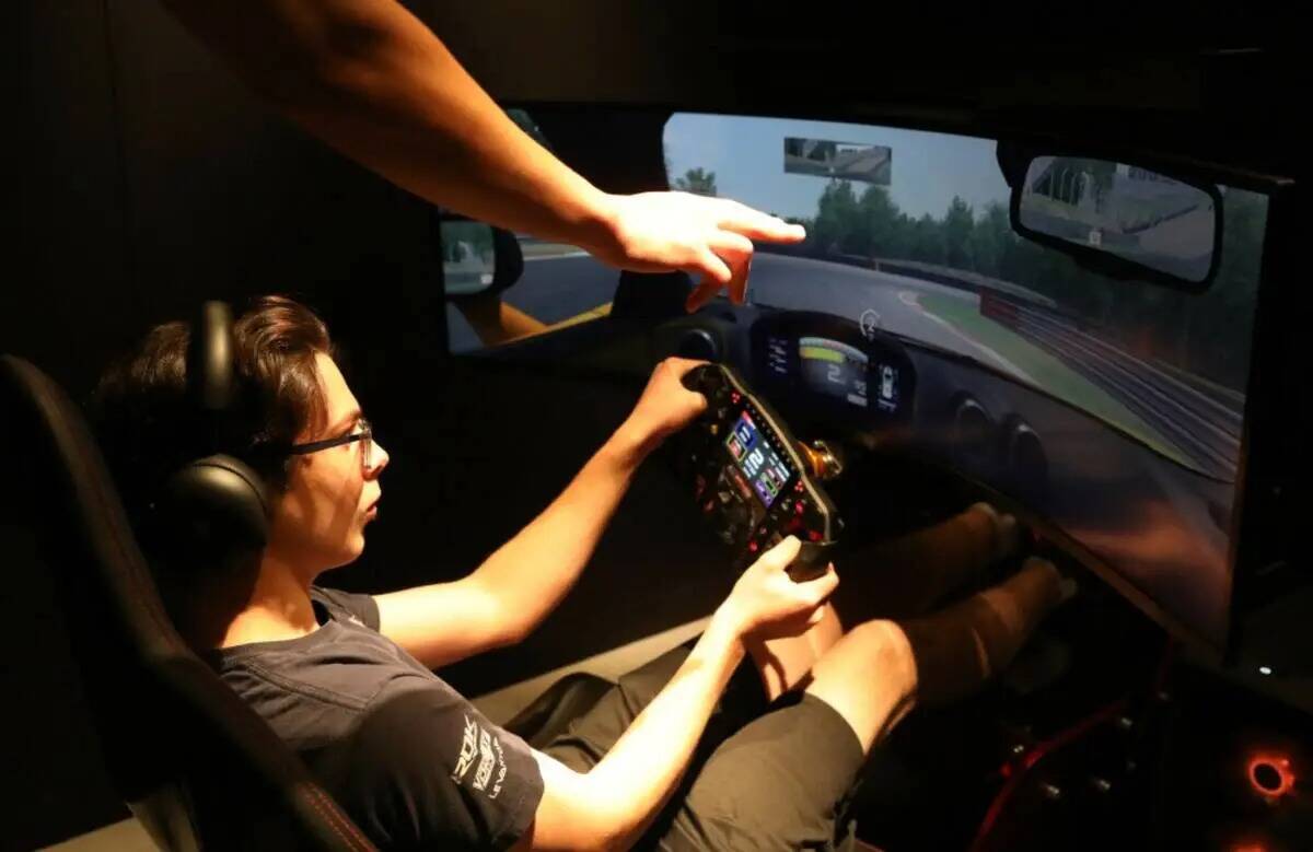 Un entrenador del simulador de McLaren ayuda a Joseph Launi, de visita desde Toronto, Canadá p ...