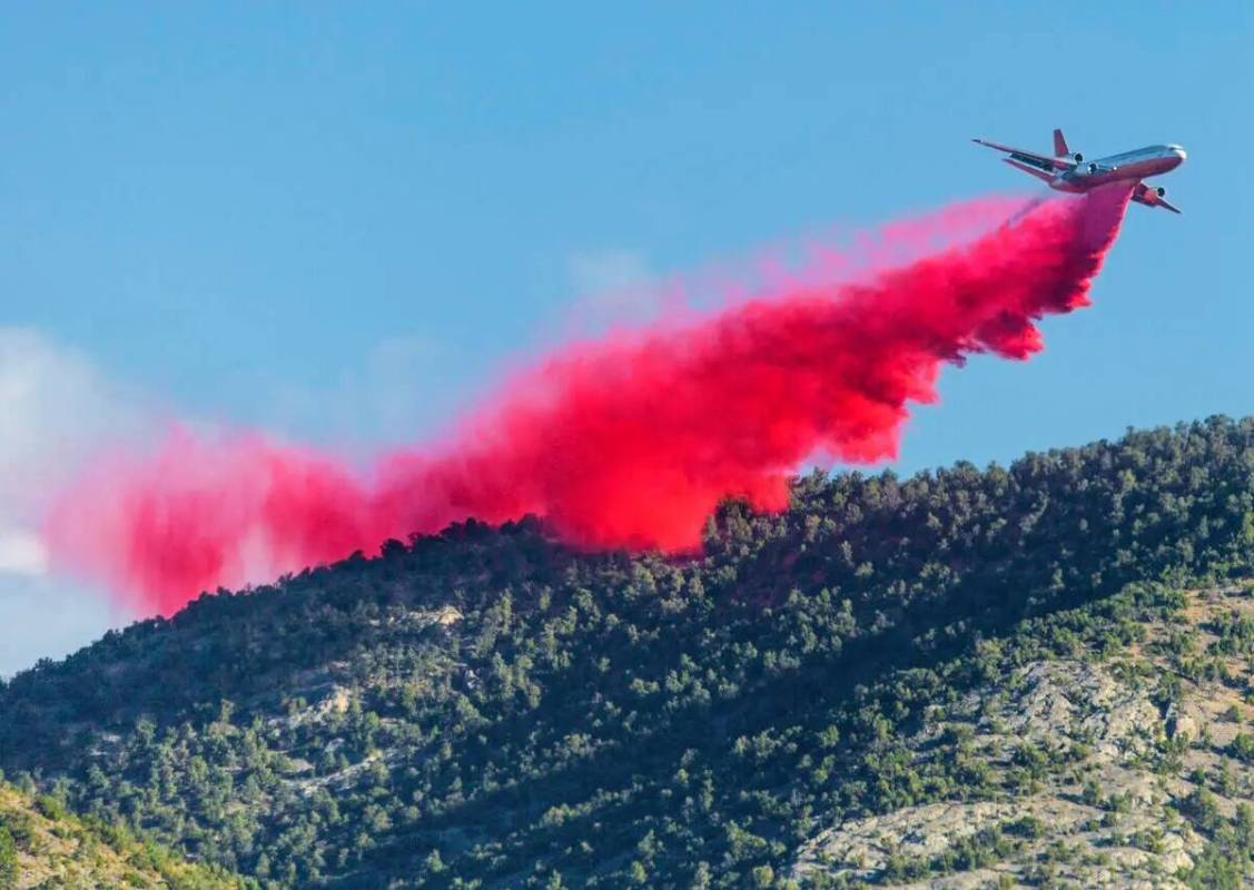 Un avión cisterna lanza retardante de incendios mientras lucha contra el incendio Mahogany en ...