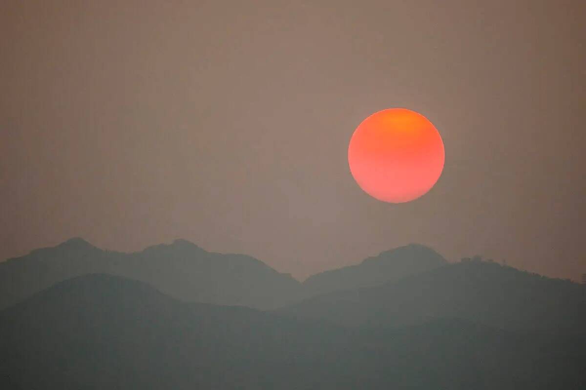 El sol, nublado por el humo de los incendios forestales en California, se pone detrás de la Sp ...