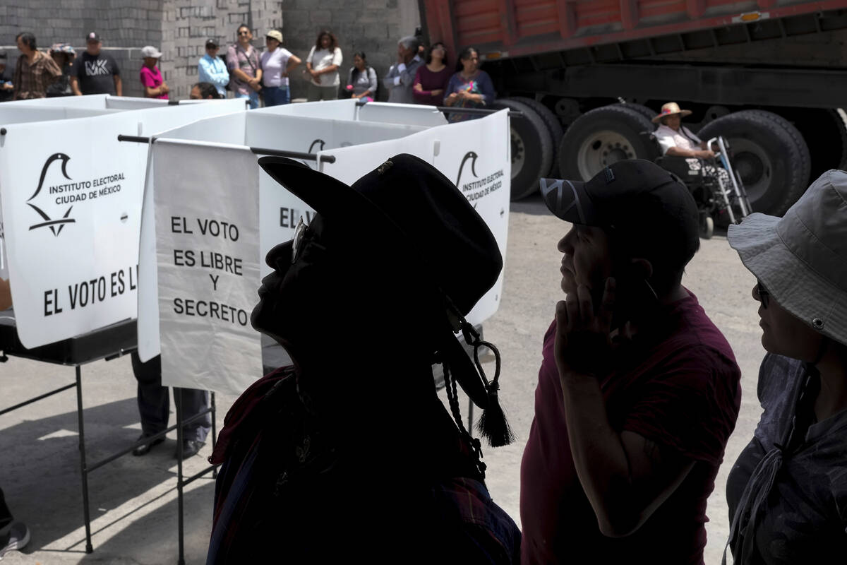 Votantes hacen fila mientras esperan su turno para emitir su voto, durante las elecciones gener ...