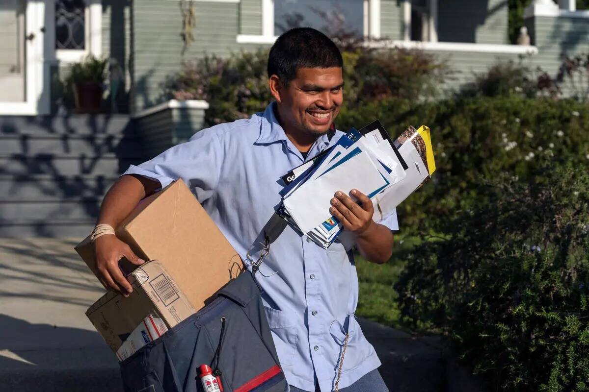 ARCHIVO - Gabriel Peña, cartero del Servicio Postal de Estados Unidos, transporta correo en Lo ...