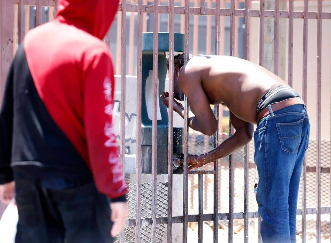 Un hombre, que se negó a dar su nombre, se refresca en la estación de recarga de agua fuera d ...