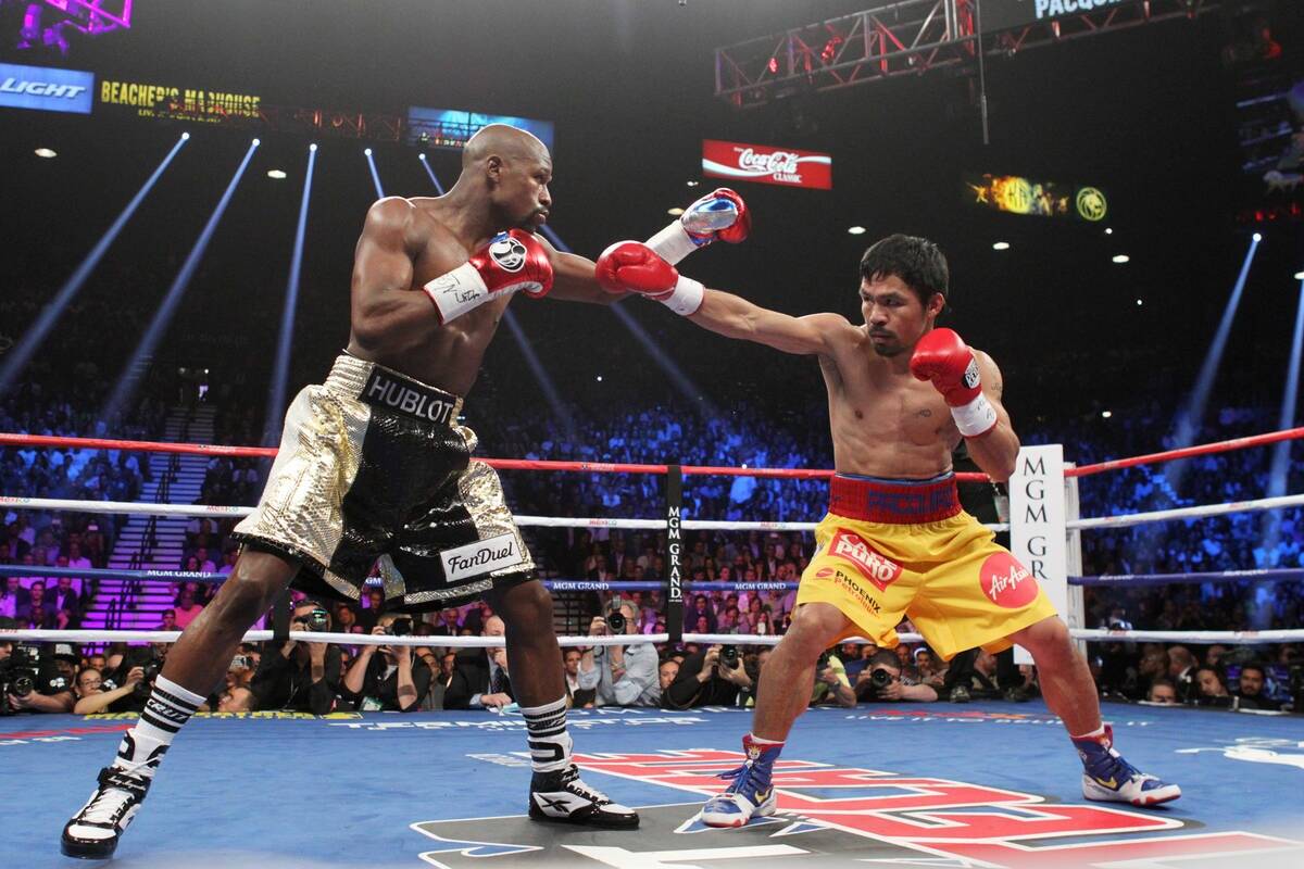 Manny Pacquiao y Floyd Mayweather Jr. intercambian golpes durante su combate de boxeo de unific ...