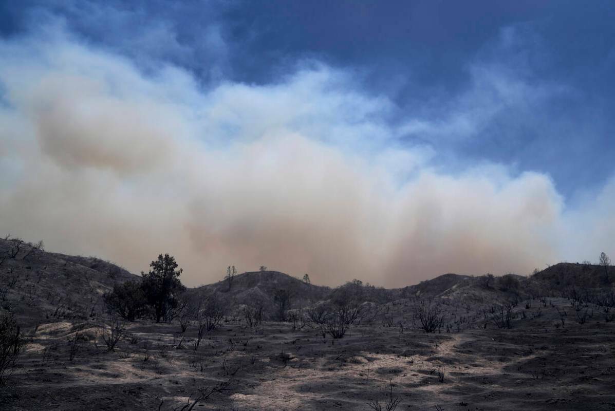 Una columna de humo del Post Fire se eleva sobre un paisaje quemado, el domingo 16 de junio de ...