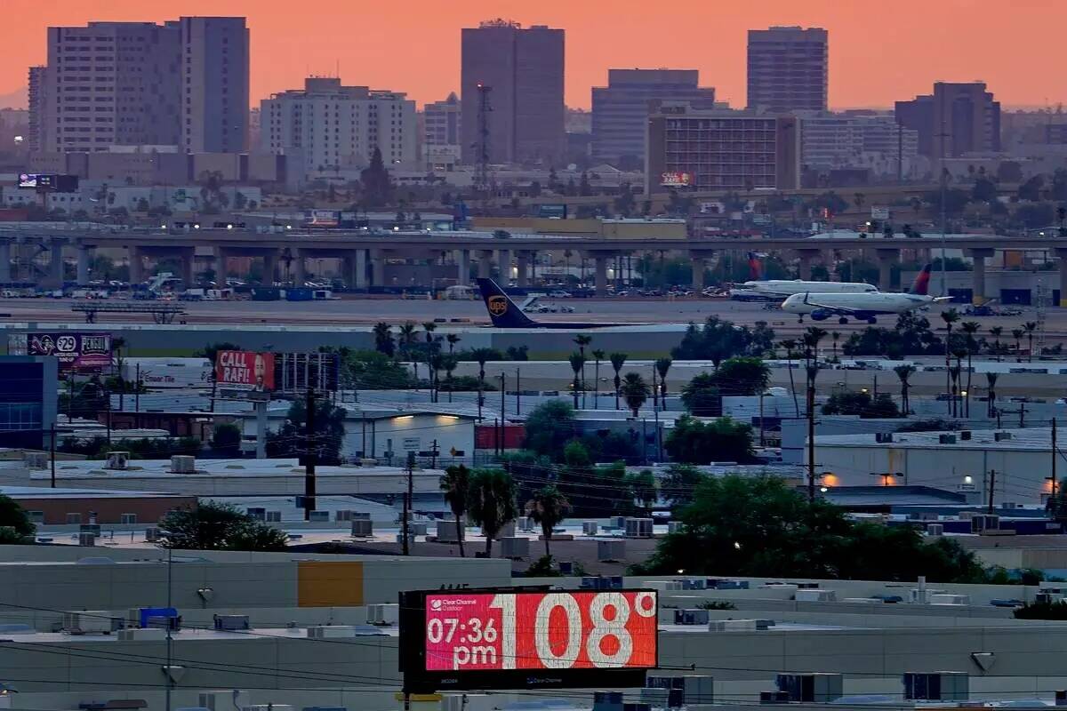 ARCHIVO - Un cartel muestra una temperatura no oficial como aviones en taxi en Sky Harbor Inter ...