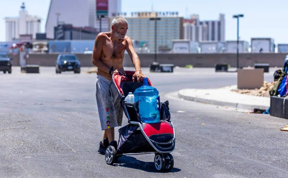 Un desamparado lleva una jarra de agua a su campamento en E. Washington Avenue, el miércoles ...