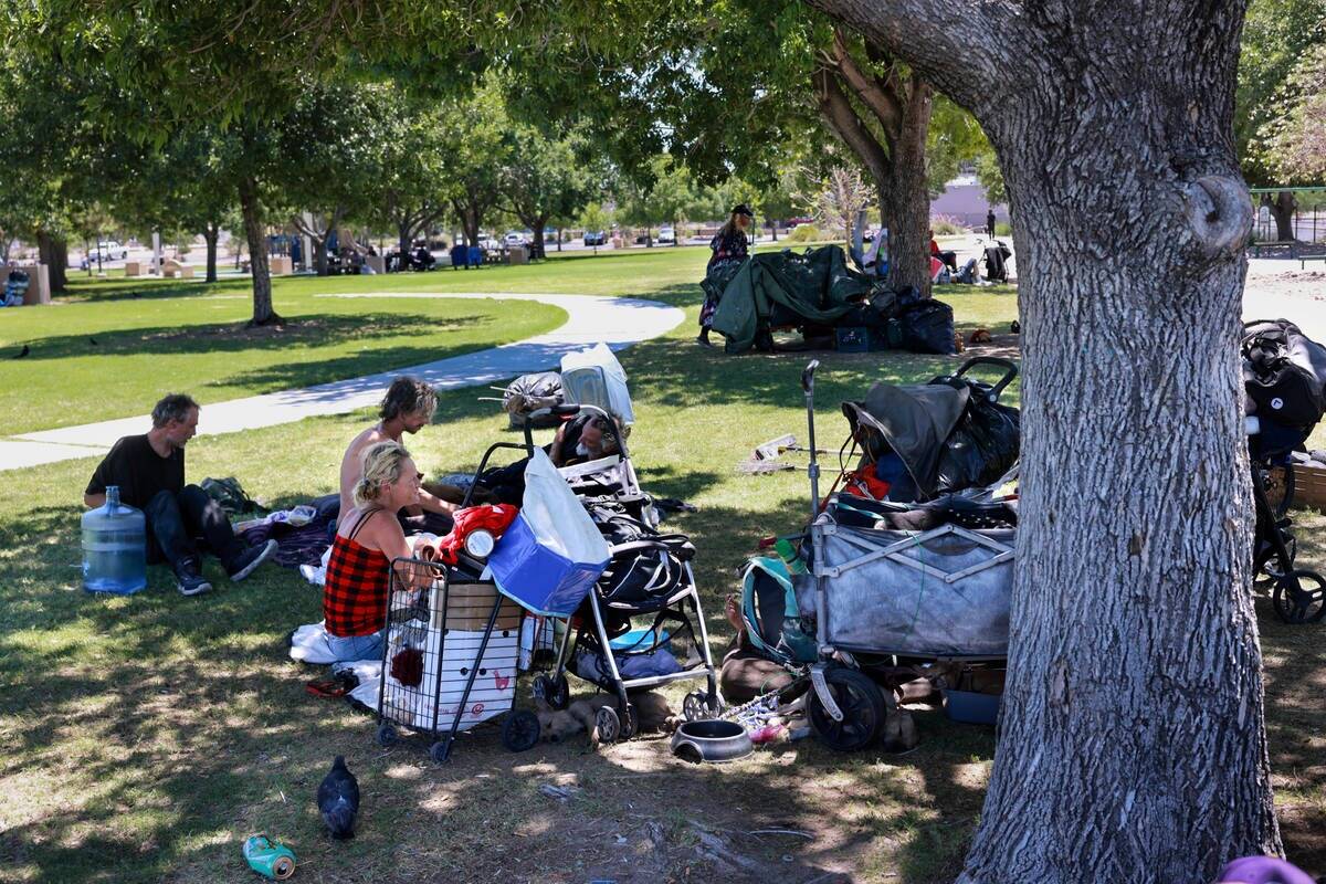 Varias personas se protegen del sol con sus pertenencias en el parque Justice Myron E. Leavitt ...