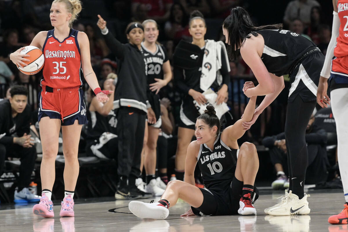 La escolta de Las Vegas Aces Kelsey Plum (10) es ayudada a levantarse tras recibir una falta de ...