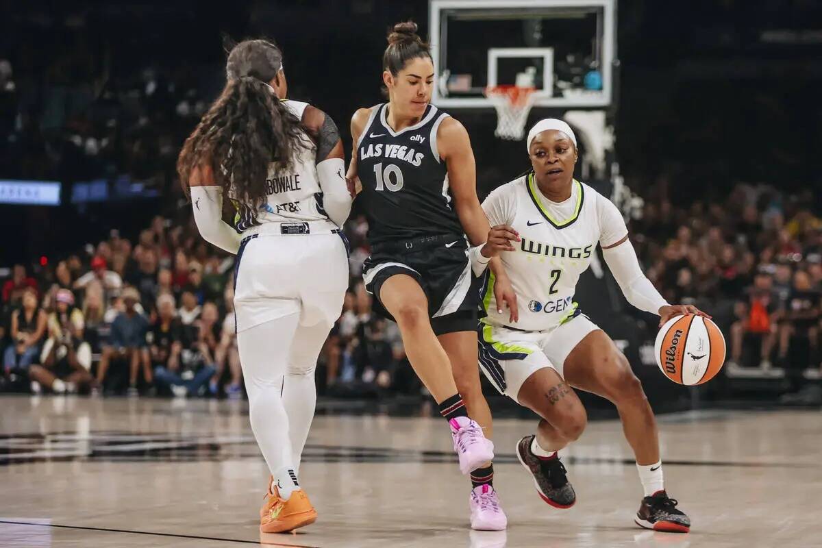 La escolta de las Aces Kelsey Plum (10) se abre paso entre la escolta de las Dallas Wings Arike ...