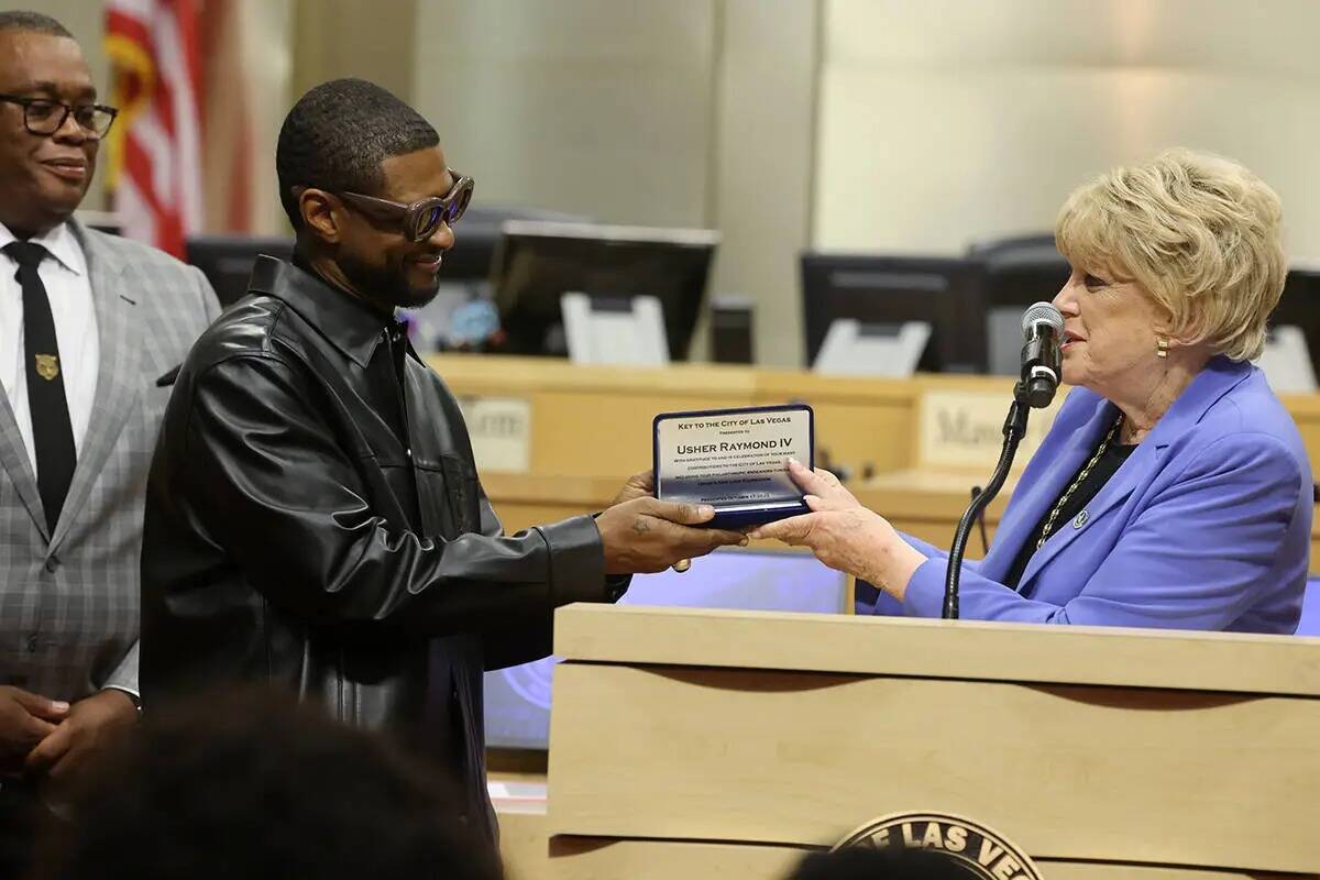 Usher, en el centro, recibe la llave de la ciudad de Las Vegas de manos de la alcaldesa Carolyn ...