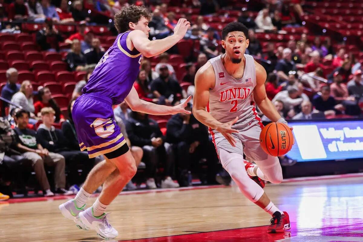 El escolta de los UNLV Rebels Justin Webster (2) driblea el balón en la pista ante el escolta ...