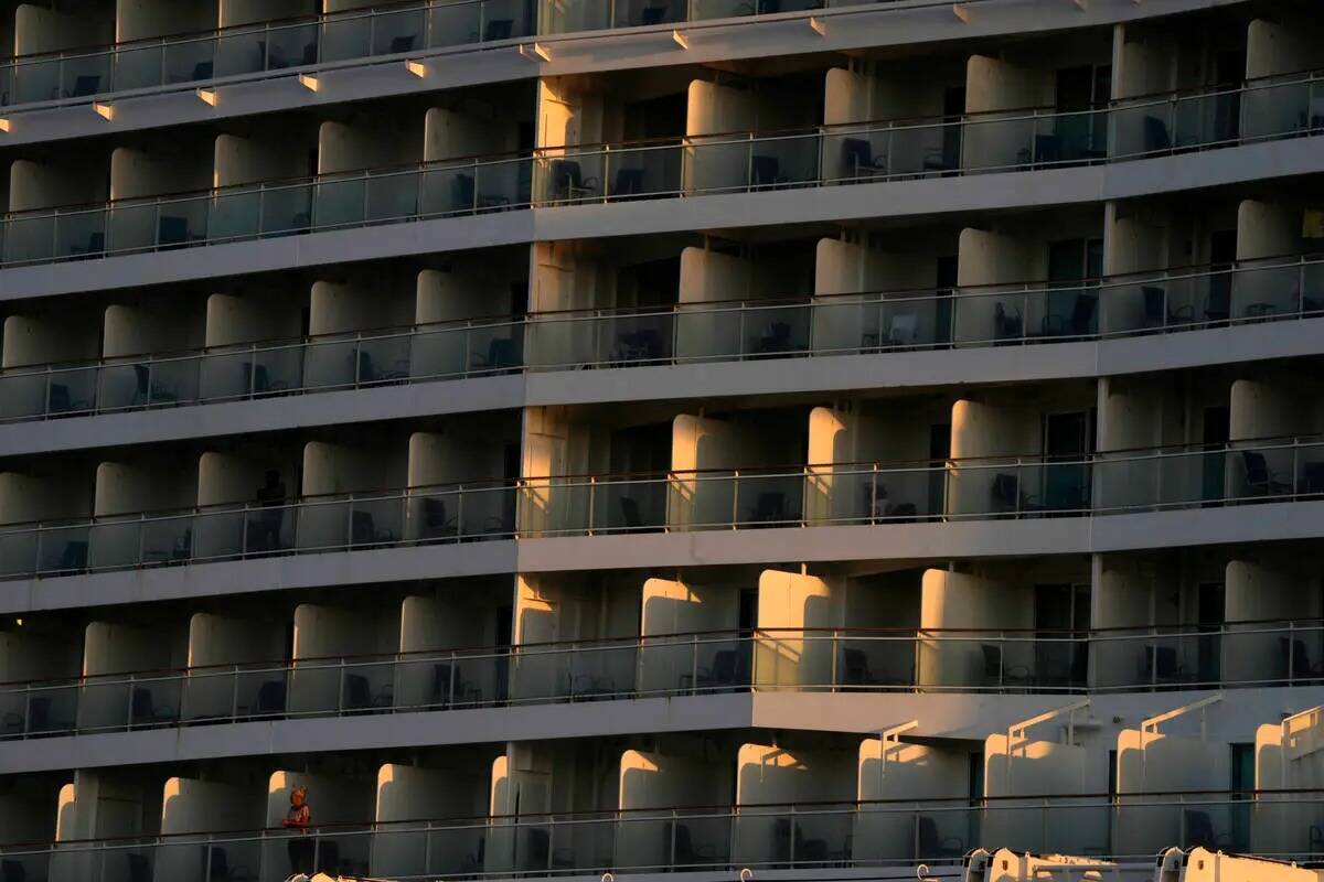 Una mujer, abajo a la izquierda, en el balcón de un crucero atracado en el puerto del Pireo, e ...