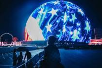 Un niño pequeño se sienta sobre unos hombros mientras observa la Sphere mientras suenan fuego ...