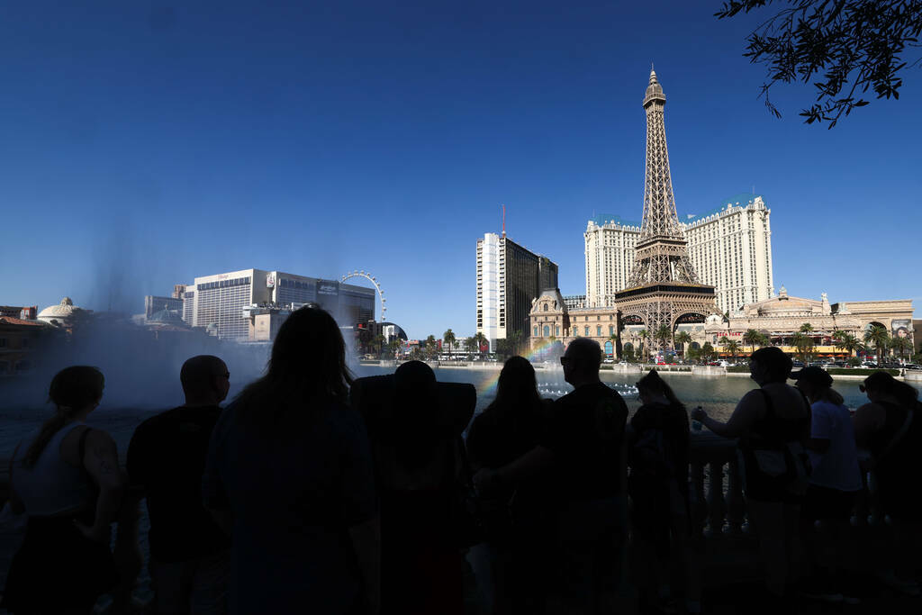 Visitantes del Strip de Las Vegas contemplan las fuentes del Bellagio desde la sombra, el viern ...