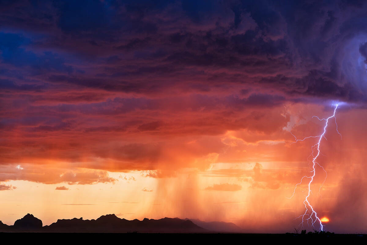 Un rayo cae junto al sol poniente mientras una tormenta eléctrica atraviesa el desierto cerca ...