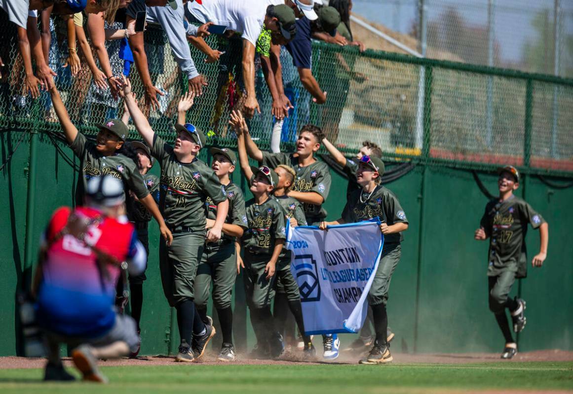 Jugadores de Nevada celebran en el campo con sus fans y la pancarta ganadora después de derrot ...