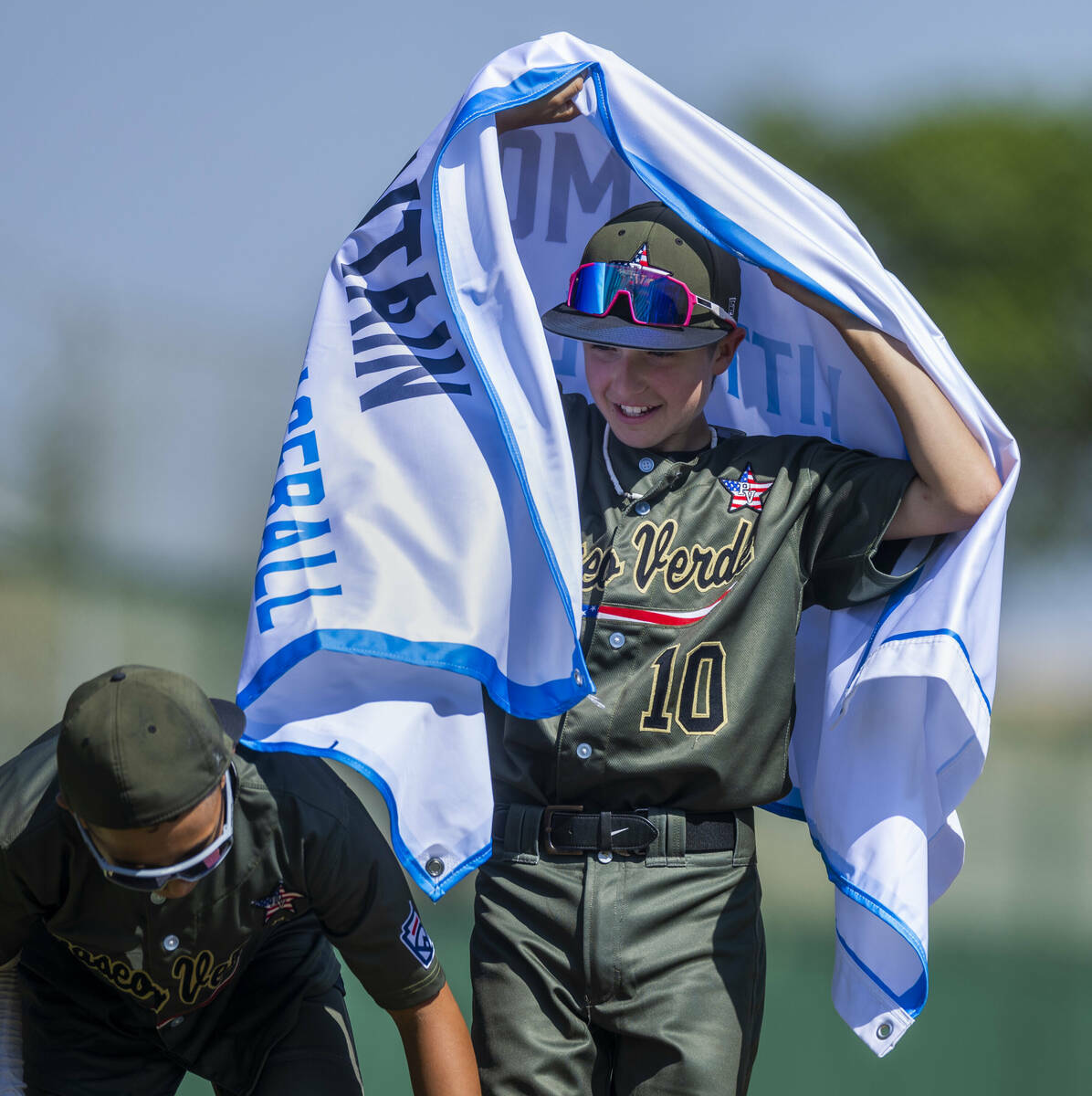 El extra hitter de Nevada Jimmy Foss (10) lleva la bandera ganadora junto al jugador Russell Mc ...