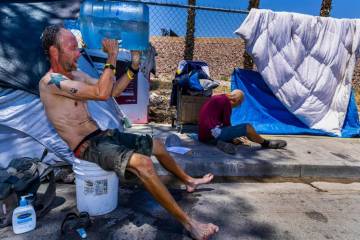 El indigente Milton John Scott III se echa una jarra de agua en la cabeza para combatir el calo ...