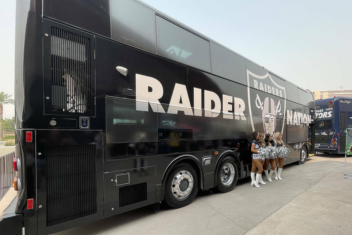 Cuatro Raiderettes de pie delante de un autobús de la RTC con una decoración de los Raiders q ...