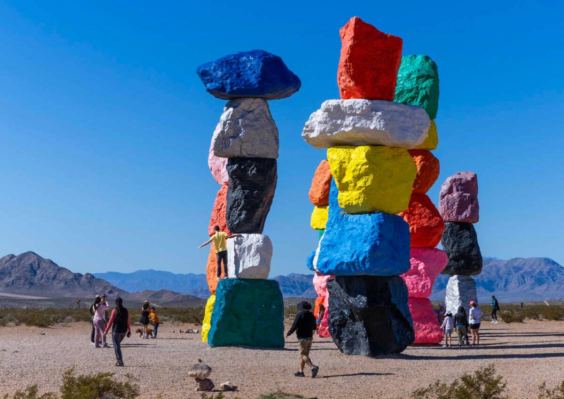 Un visitante se para en lo alto de una de las rocas mientras él y otras personas se detienen a ...