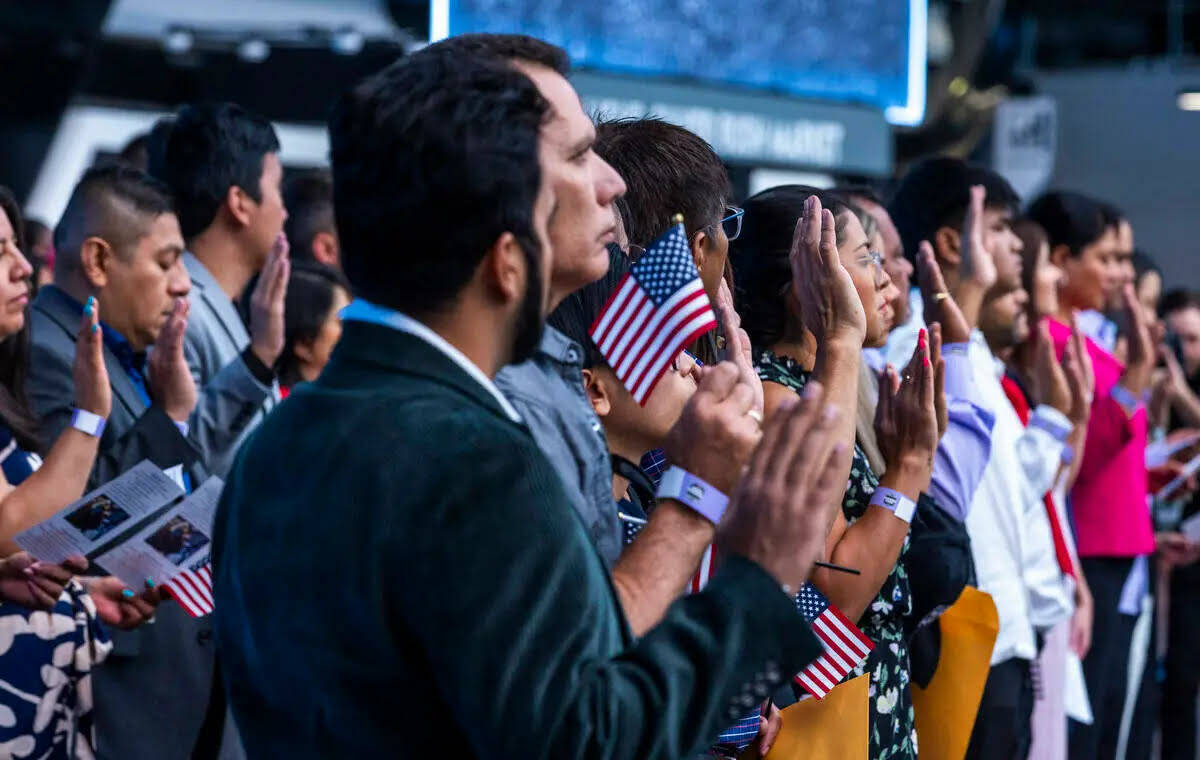 Los aspirantes levantan las manos para el Juramento de Lealtad durante una ceremonia de natural ...