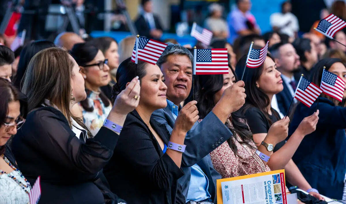 Los nuevos ciudadanos agitan banderas durante una ceremonia de naturalización en el Allegiant ...