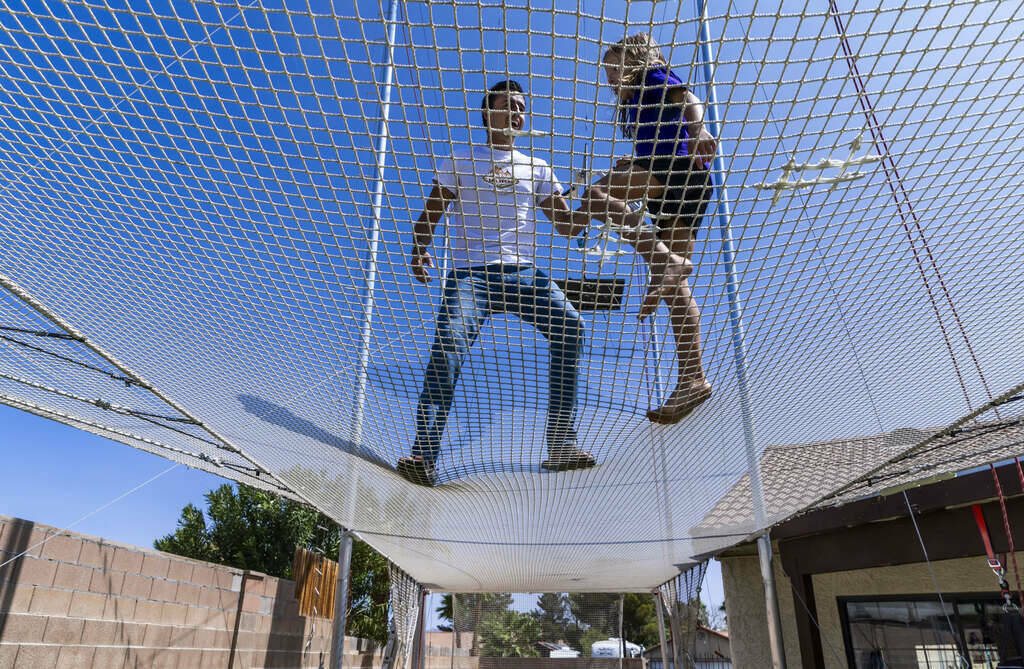 Renato Fernandes con su hija Katalina encima de la red en el trapecio de su patio trasero, el s ...