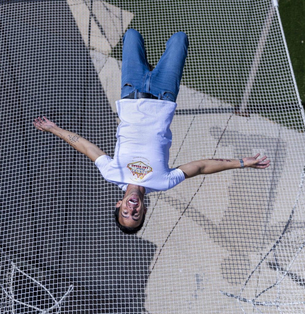 Renato Fernandes completa una voltereta hacia atrás encima de la red en su trapecio del patio ...