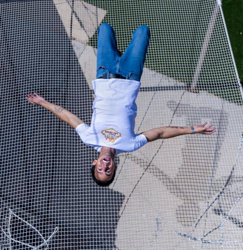 Renato Fernandes completa una voltereta hacia atrás encima de la red en su trapecio del patio ...