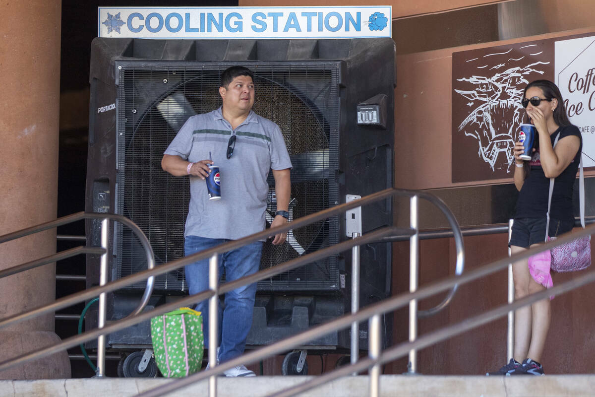 Turistas a la sombra cerca de un gran ventilador en la estación de enfriamiento en la Presa Ho ...