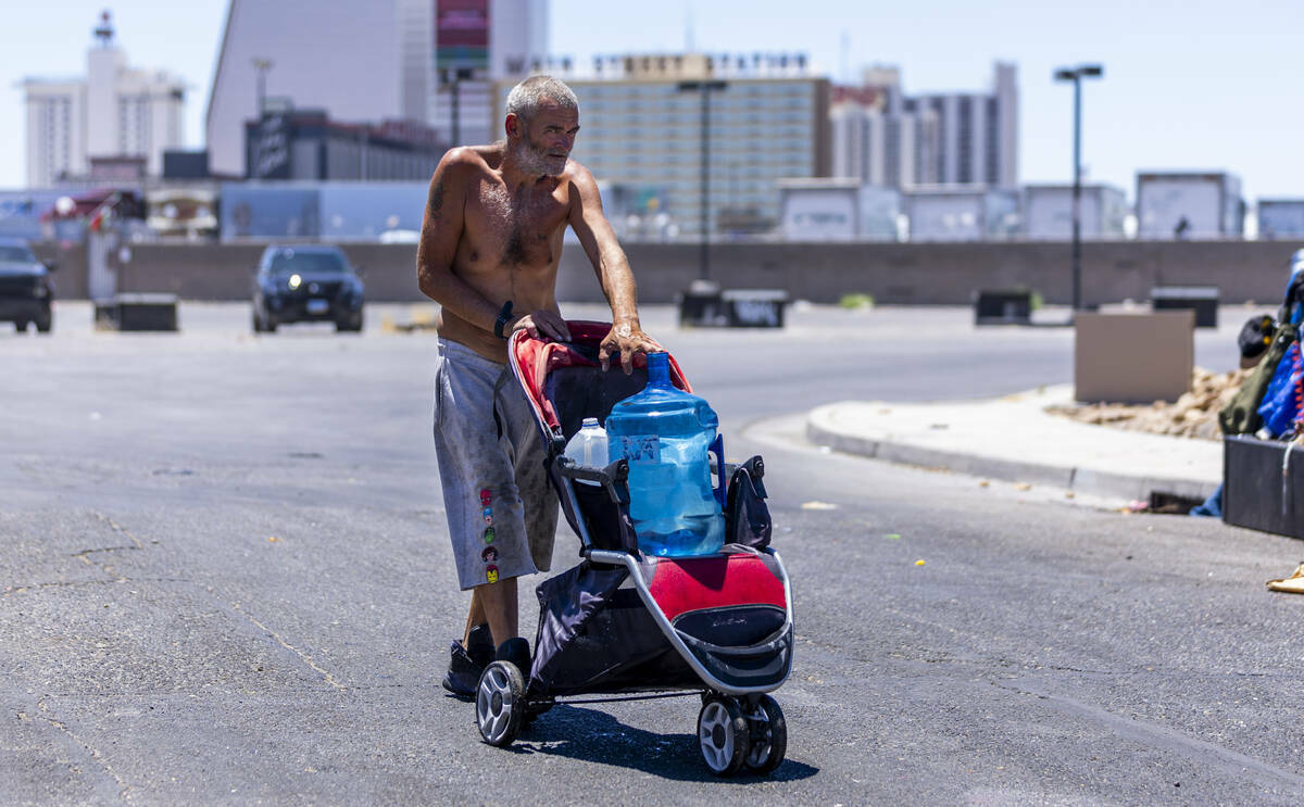 Un indigente lleva un garrafón de agua a su campamento a lo largo de E. Washington Ave., el mi ...