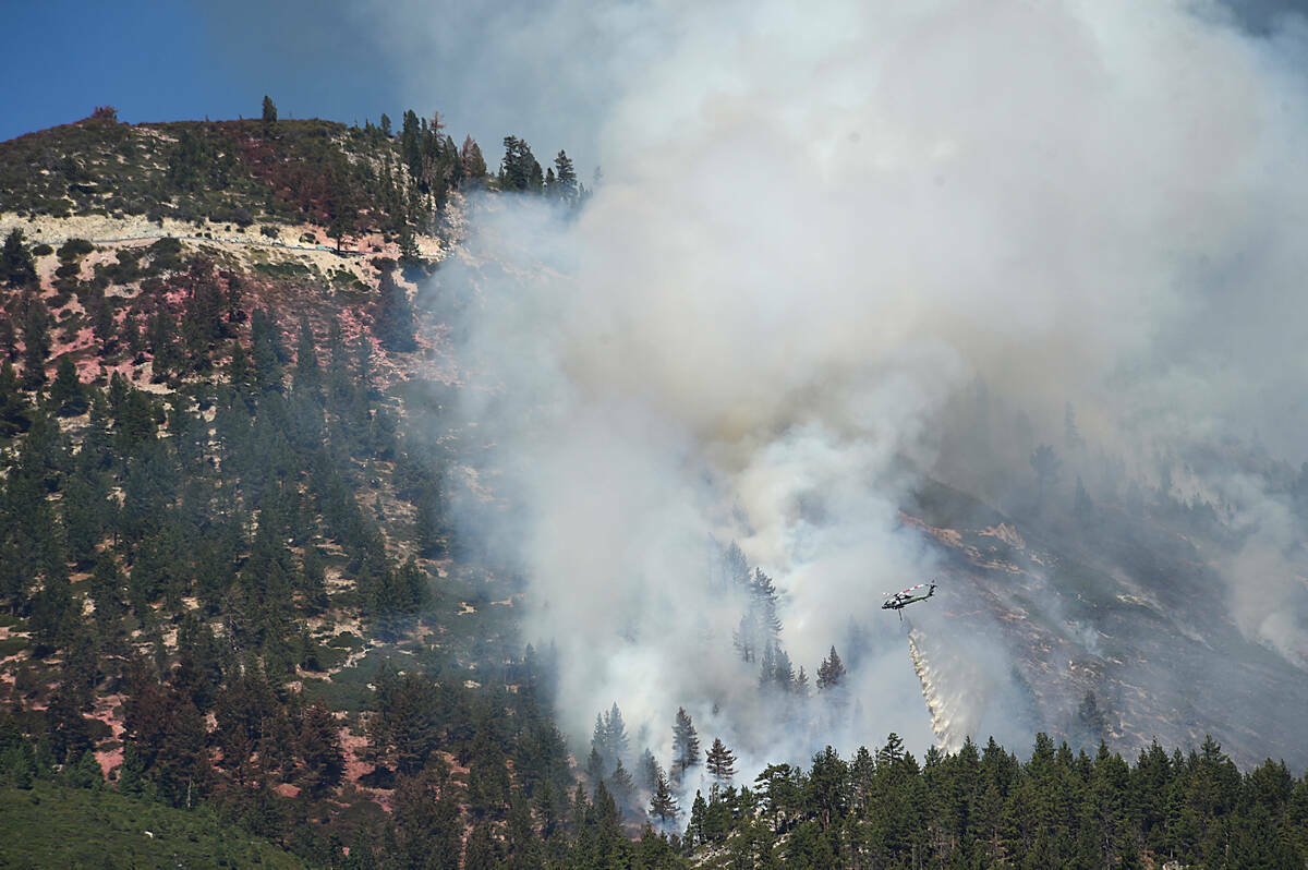 Un helicóptero lanza agua mientras el Incendio de Davis sigue ardiendo en las montañas al sur ...